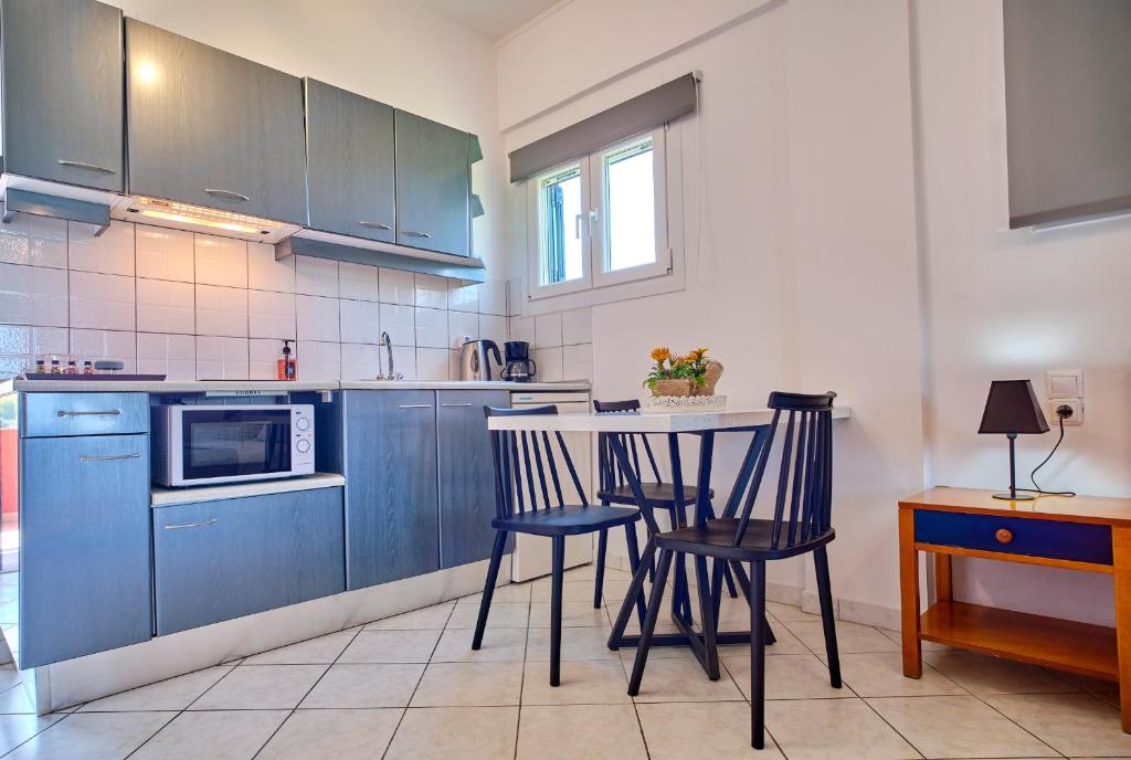 a kitchen with blue cabinets and a table and chairs at Logas Beach Studios Peroulades Corfu in Peroulades