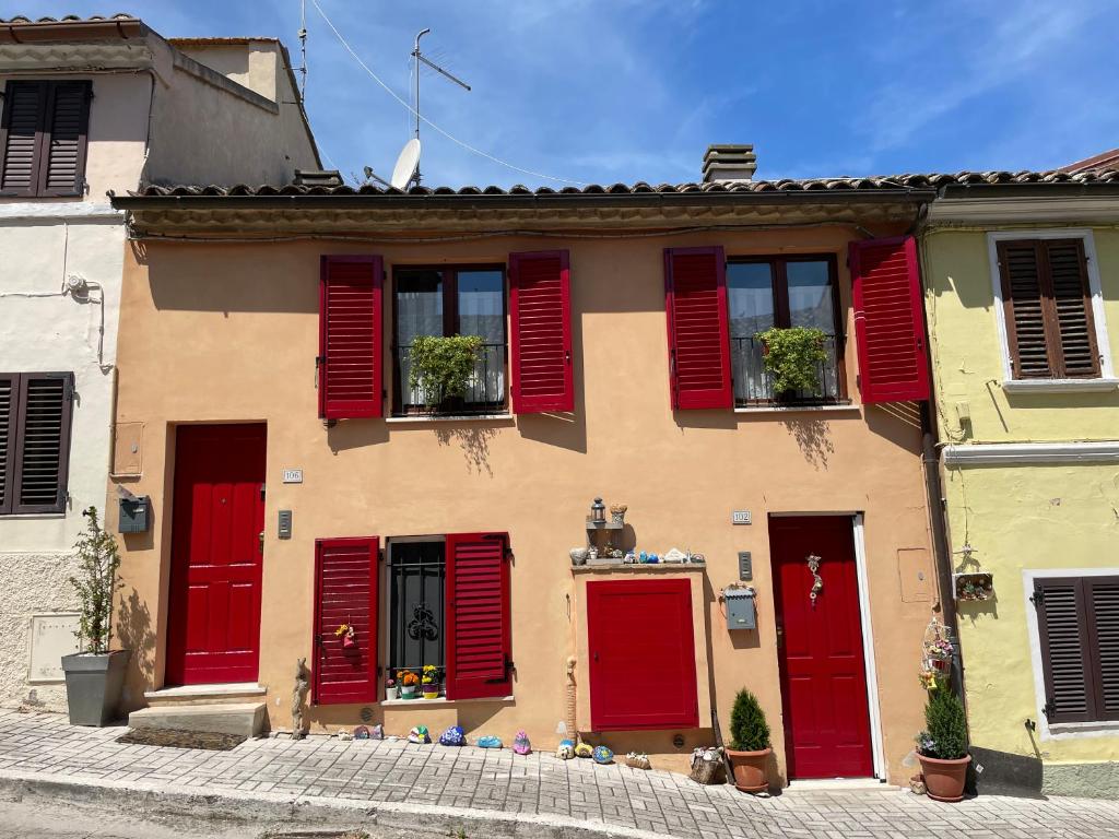 una casa con persianas rojas en una calle en Appartamento incantevole sull'antica via Lauretana en Loreto