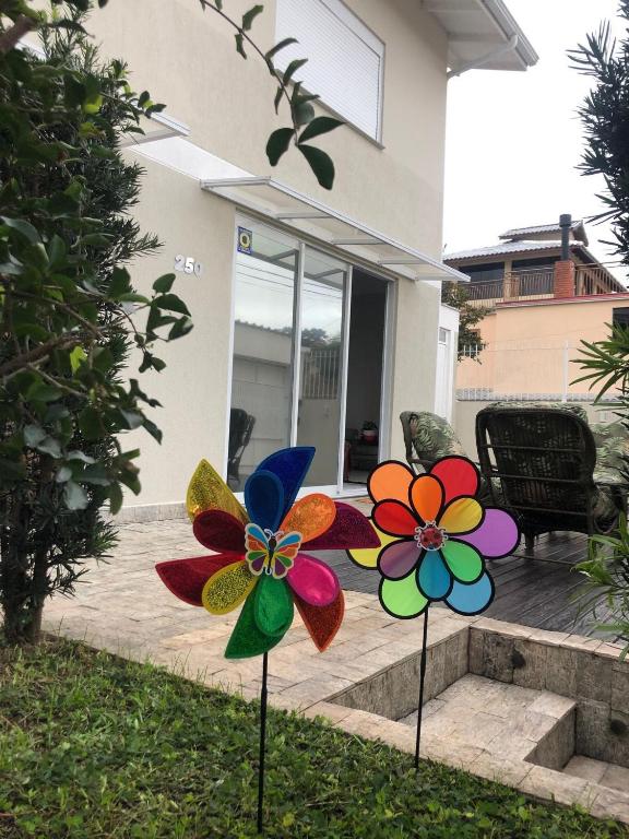 two colorful flowers on posts in front of a house at Solar dos Cataventos: Linda Casa com Piscina e Jacuzi in Florianópolis