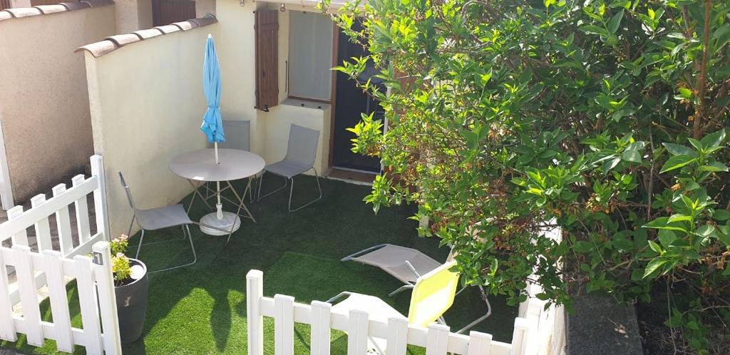une terrasse avec une clôture blanche, une table et des chaises dans l'établissement Maisonnette studio jardinet, à Gréoux-les-Bains