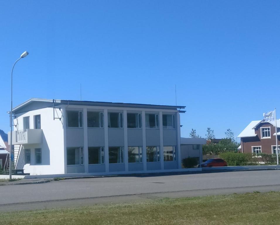 ein weißes Gebäude mit Fenstern und einer Straße in der Unterkunft Síma Apartment in Flateyri