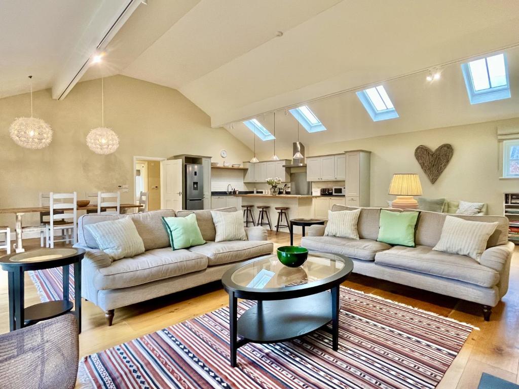 a living room with couches and tables and a kitchen at Beaufort Barn by Inspire Stays in Bignor