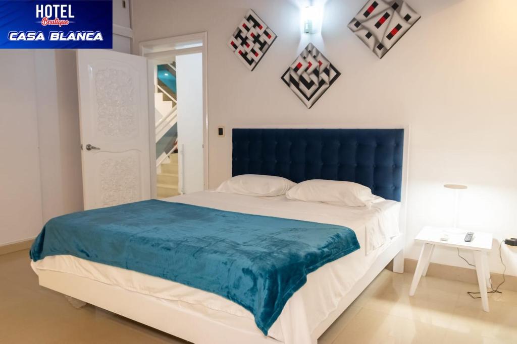 a bedroom with a large bed with a blue headboard at Hotel Boutique Casa Blanca Zarzal in Zarzal