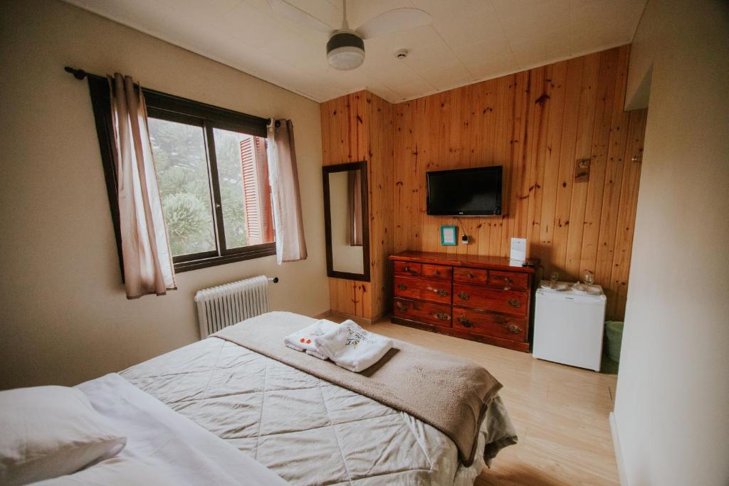 una camera da letto con un letto, una cassettiera e una televisione di Pousada Casa da Paz a Gramado