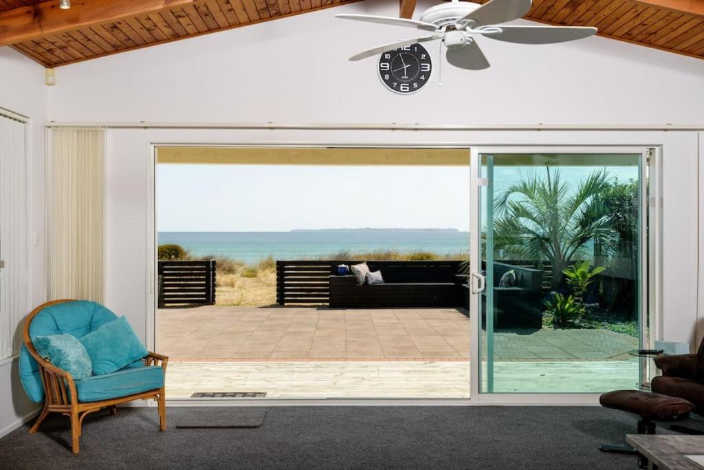 a living room with a ceiling fan and a sliding glass door at Pats Place on the Beach in Papamoa