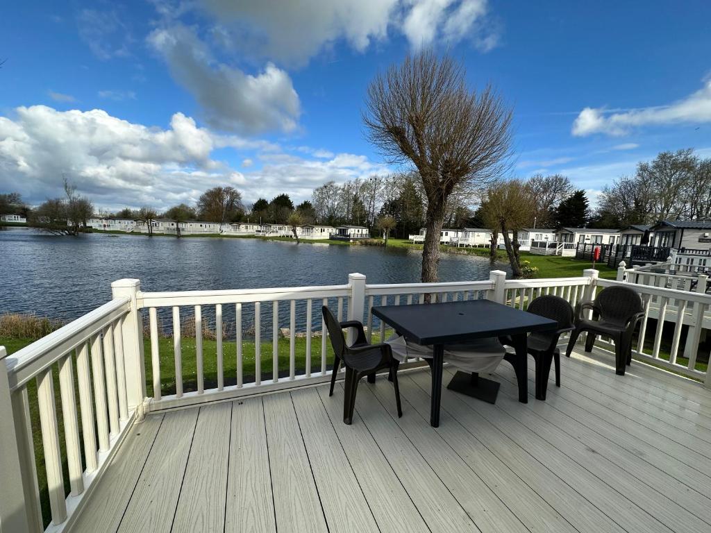 a deck with a table and chairs and a view of a river at Waterside Lodge in South Cerney