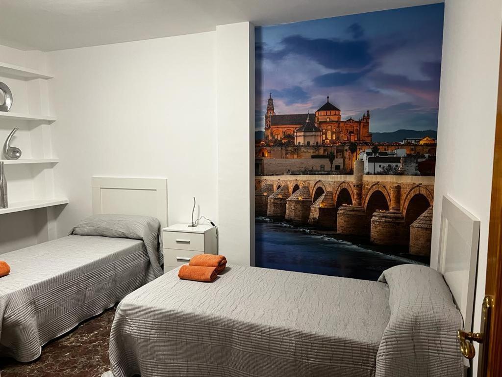une chambre avec deux lits et un tableau représentant un pont dans l'établissement GRACIA, à Cordoue
