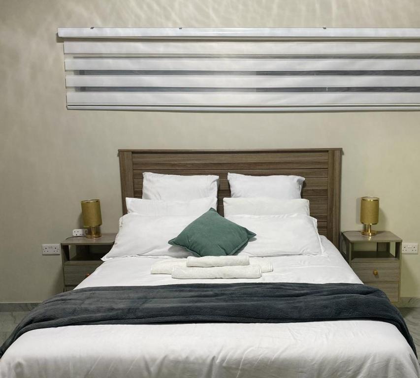 a large bed with white sheets and a green pillow at modern, two-story luxury house in Gaborone