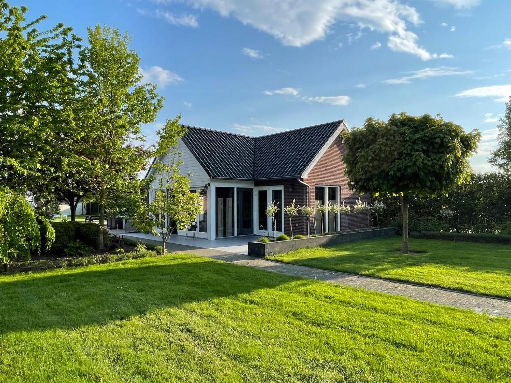 una casa con un césped verde delante de ella en Gastenverblijf bij de Buuren en Dirksland
