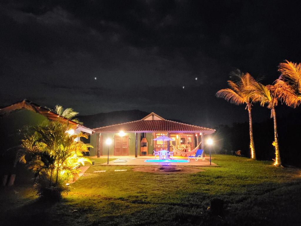 a house lit up at night with palm trees at chale da montanha in Taubaté