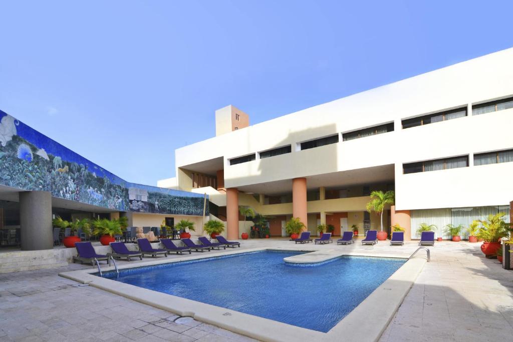 a building with a swimming pool in front of a building at Hotel Los Aluxes in Mérida