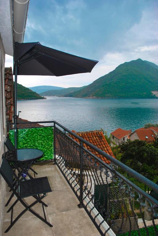 a balcony with a table and an umbrella and a lake at Apartment Mediterraneo Blue Sky in Perast