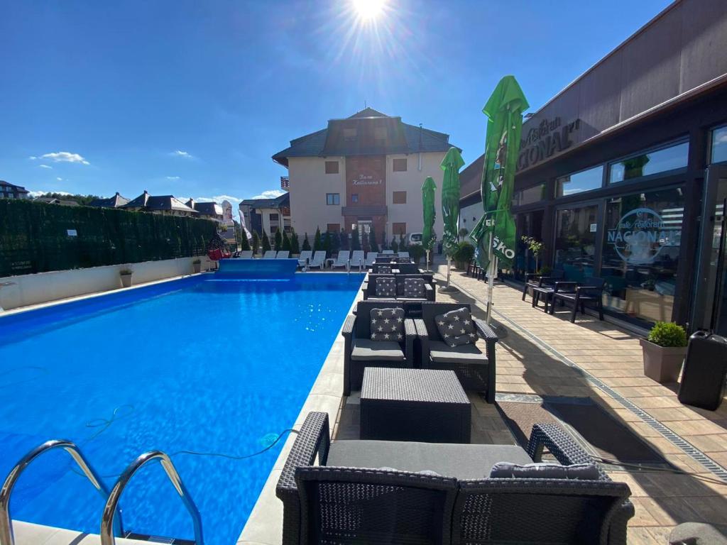 a swimming pool with lounge chairs next to a building at Spa & Wellness, apartman Sun & Snow in Zlatibor