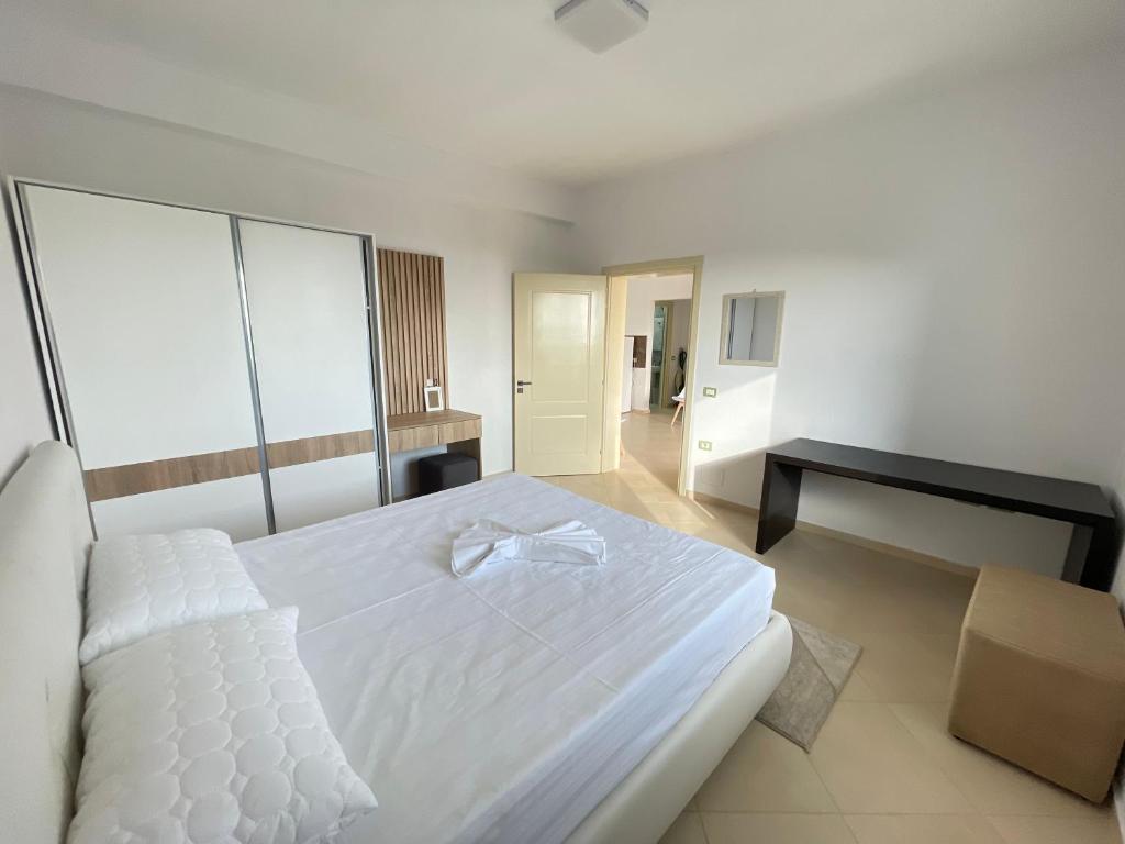 ein Schlafzimmer mit einem weißen Bett und einem schwarzen Schreibtisch in der Unterkunft Villa Gaia in Vlorë