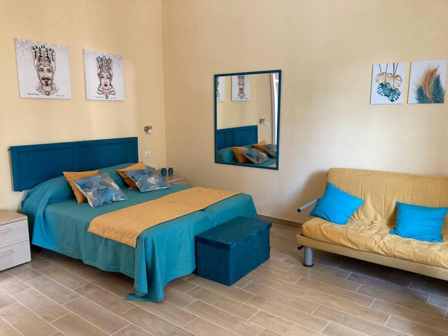 a bedroom with a blue bed and a couch at Casa Dalfea in Mazara del Vallo
