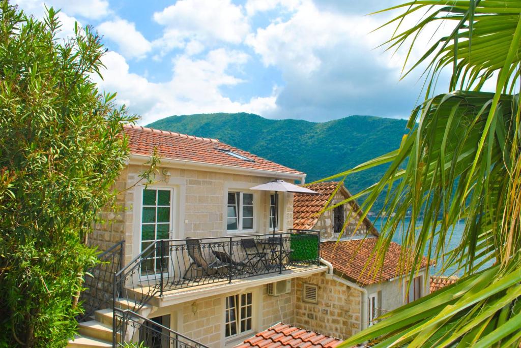 a house with a balcony with a table and chairs at Apartment Mediterraneo Blue Sky in Perast