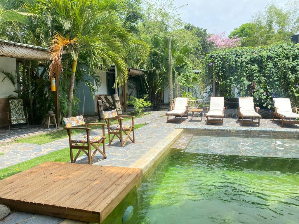 uma piscina com cadeiras e um banco de madeira ao lado de uma casa em Ekaa Hotel em Palomino
