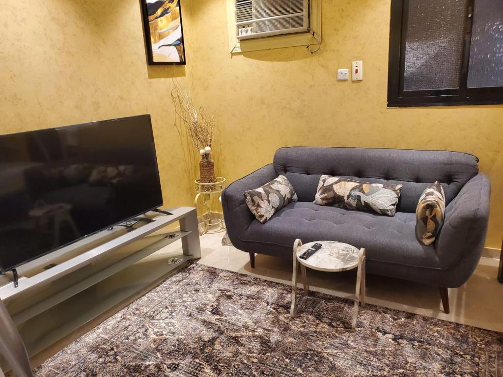 شقة لين طيبة للعوائل Leen Taibah Ap. for family's في المدينة المنورة: غرفة معيشة مع أريكة وتلفزيون بشاشة مسطحة