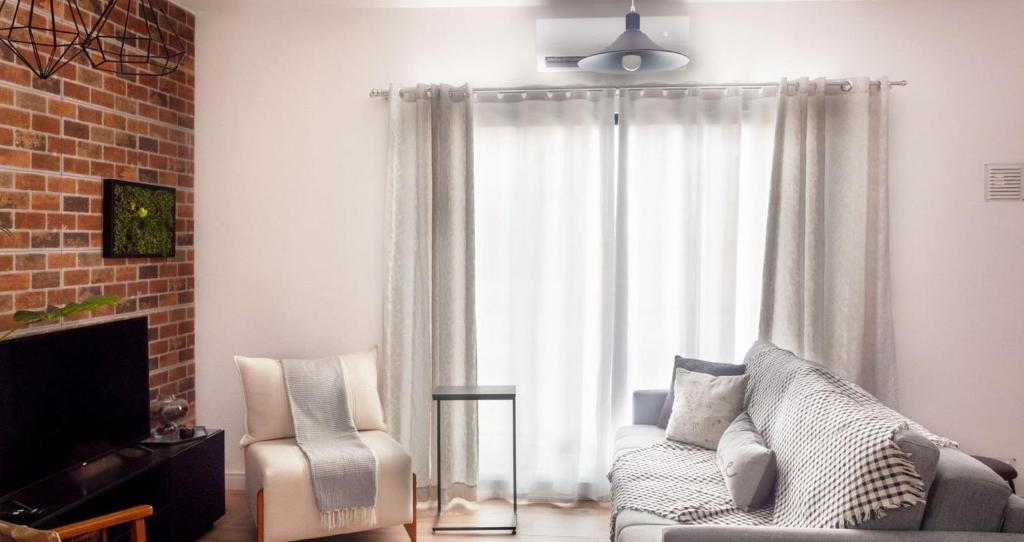 a living room with a couch and a chair and a window at Apto aconchegante e familiar em BC in Balneário Camboriú