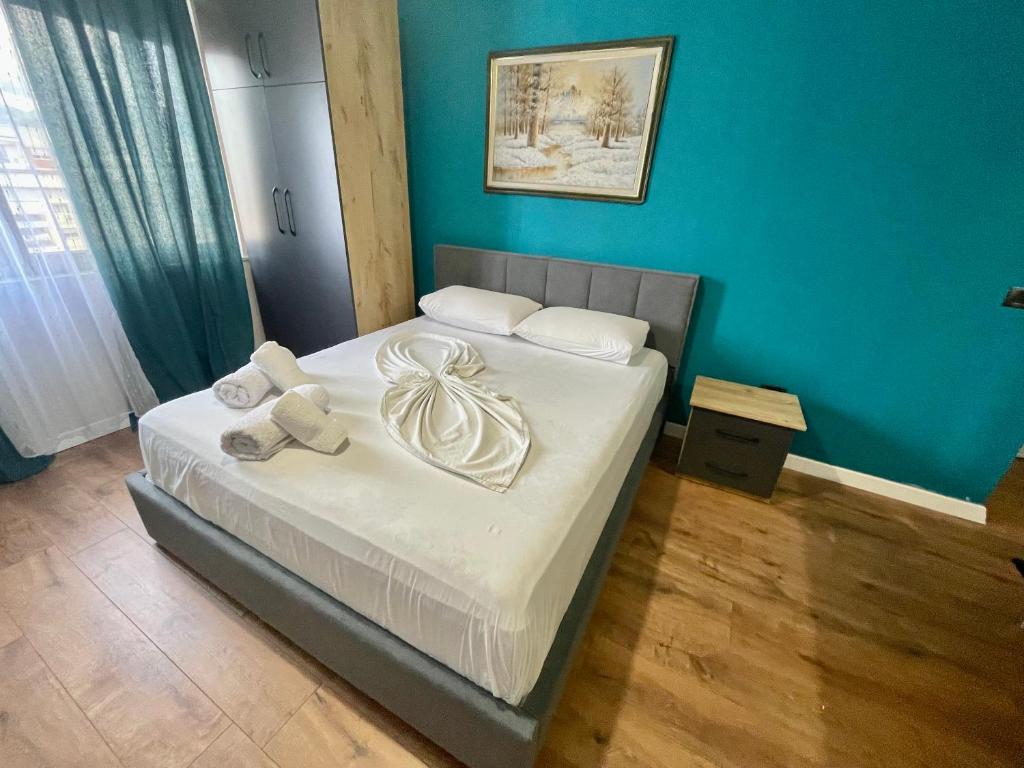 a bed in a room with a blue wall at Keon superb studio apartament in Tirana