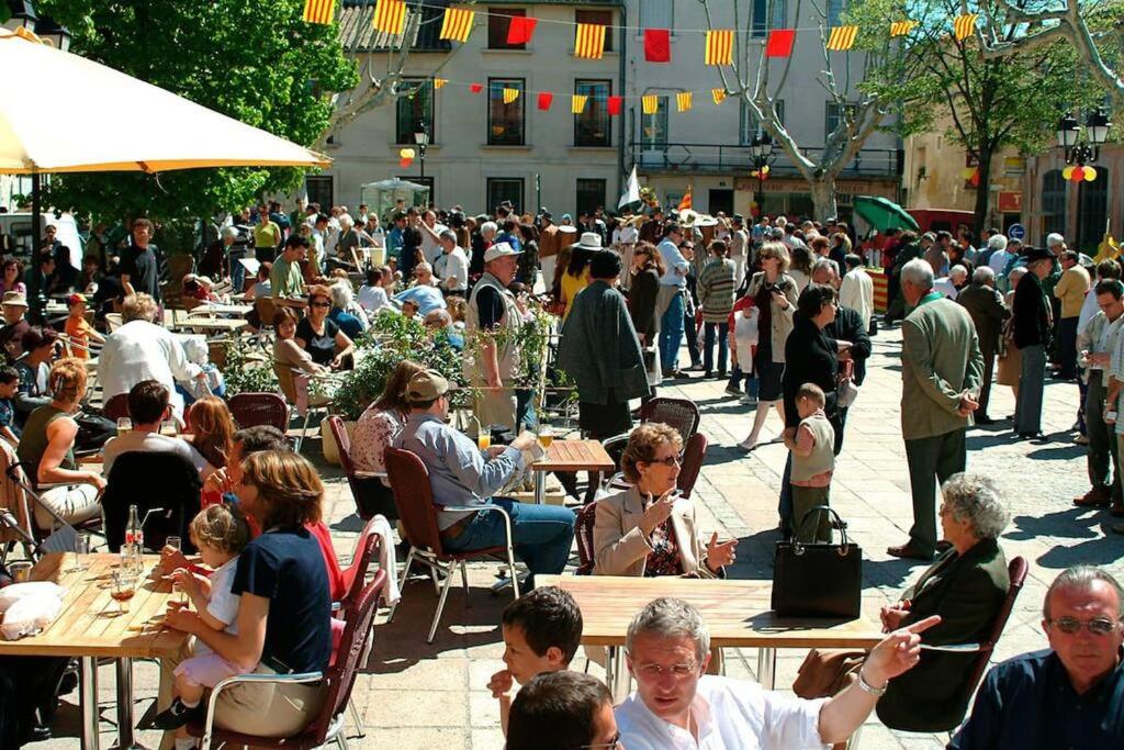 a large crowd of people sitting at tables in a courtyard at La Cigale - Vieux Village - Charmante Maisonnette climatisée avec Jardin in Villeneuve-lès-Avignon