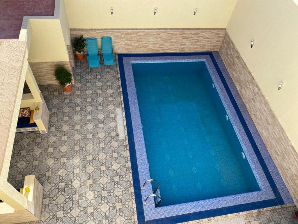 an overhead view of a swimming pool with blue chairs at Villa Ihaddadene in Nador