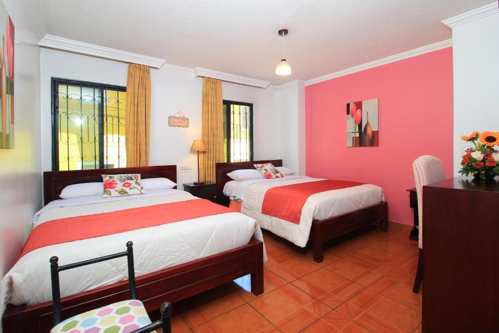 een slaapkamer met 2 bedden en roze muren bij La Rosario in Quito
