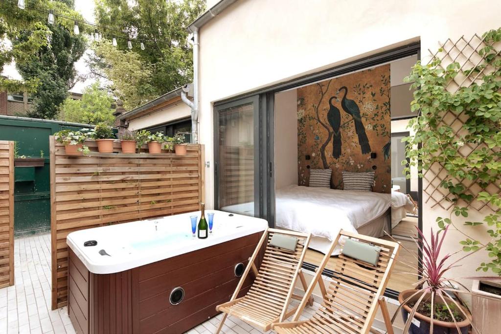 Elle comprend un balcon avec une baignoire et un lit sur une terrasse. dans l'établissement PARIS Maison Exception Terrasse Jacuzzi Parking gratuit, à Saint-Ouen