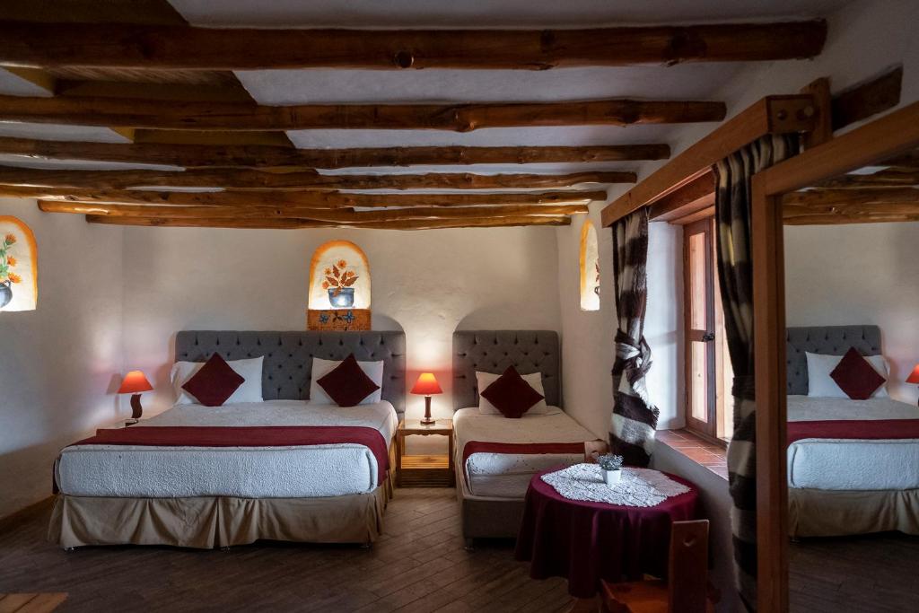 a hotel room with two beds and a table at Hotel Spa Casa de Adobe Villa de Leyva in Villa de Leyva