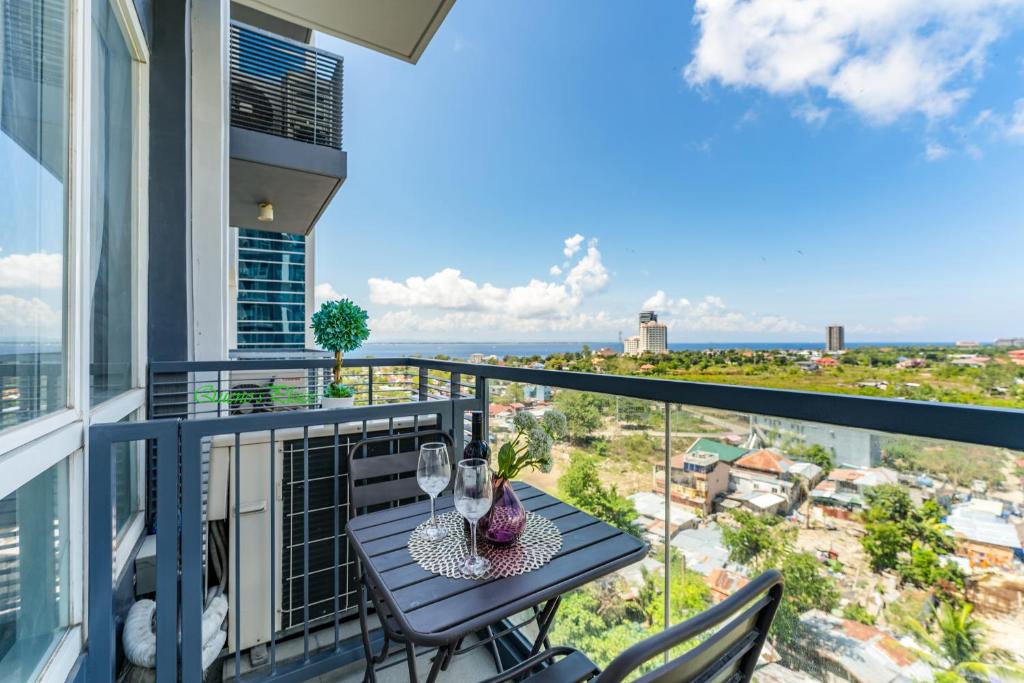 a balcony with a table with wine glasses on it at Mactan Newtown - 1BR Stunning Ocean View and City View in Mactan