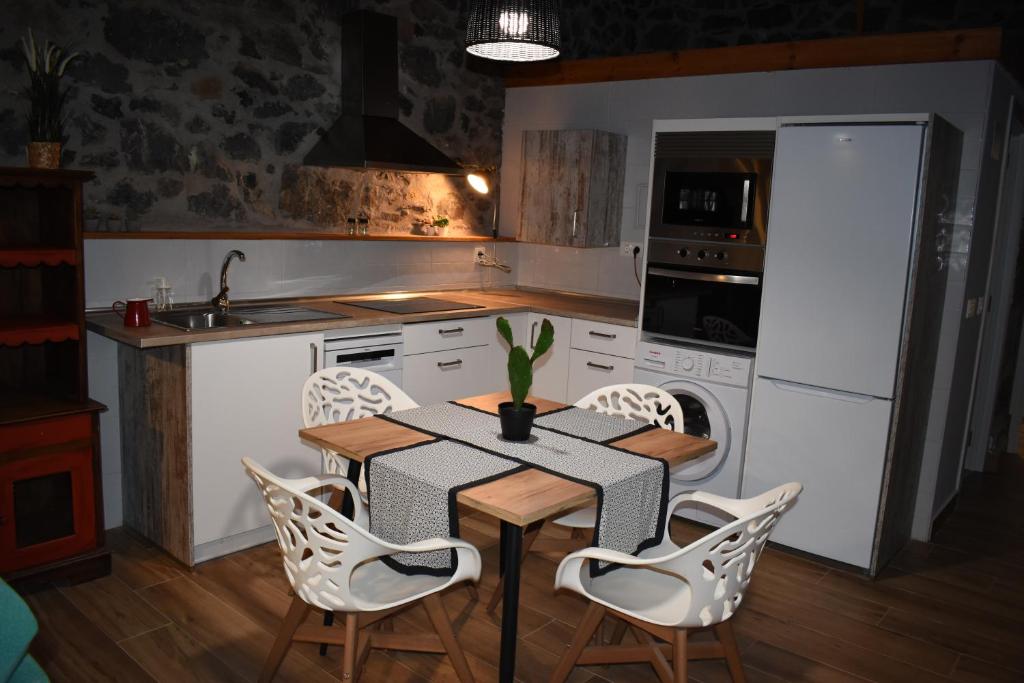 una cocina con mesa y sillas y una cocina con electrodomésticos blancos. en LA ANTIGUA CUADRA precioso apartamento de piedra con jardín, barbacoa y acceso al río, en Ramales de la Victoria