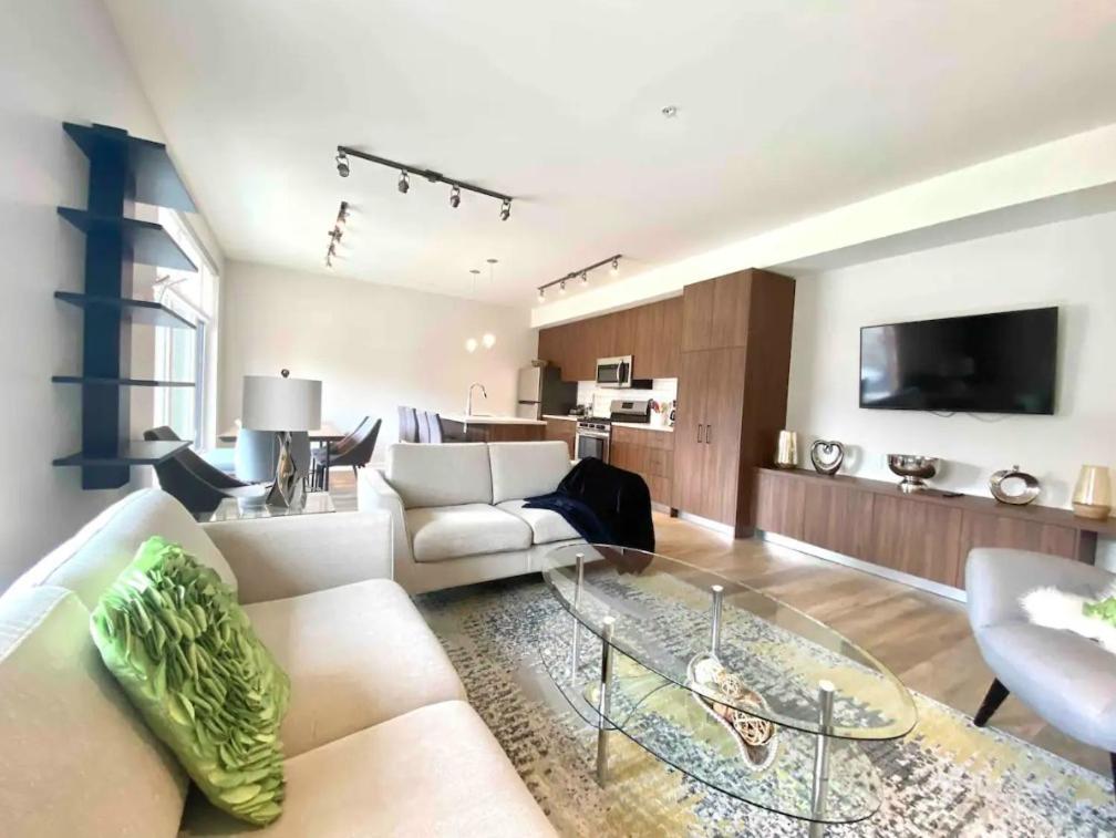 uma sala de estar com um sofá branco e uma mesa de vidro em Brand New 3-Bedroom Condo in the Heart of Sidney em Sidney