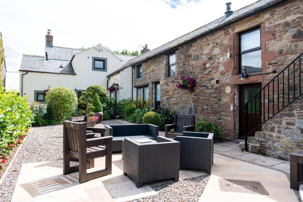 eine Terrasse mit Tischen und Stühlen vor einem Gebäude in der Unterkunft Brae Fell Cottage, Sebergham, Nr Caldbeck in Sebergham