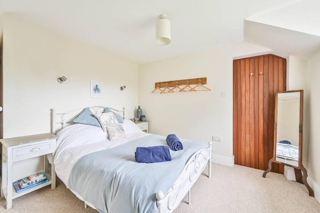 ein Schlafzimmer mit einem großen weißen Bett mit blauen Kissen in der Unterkunft Wykeham Coach House in Looe