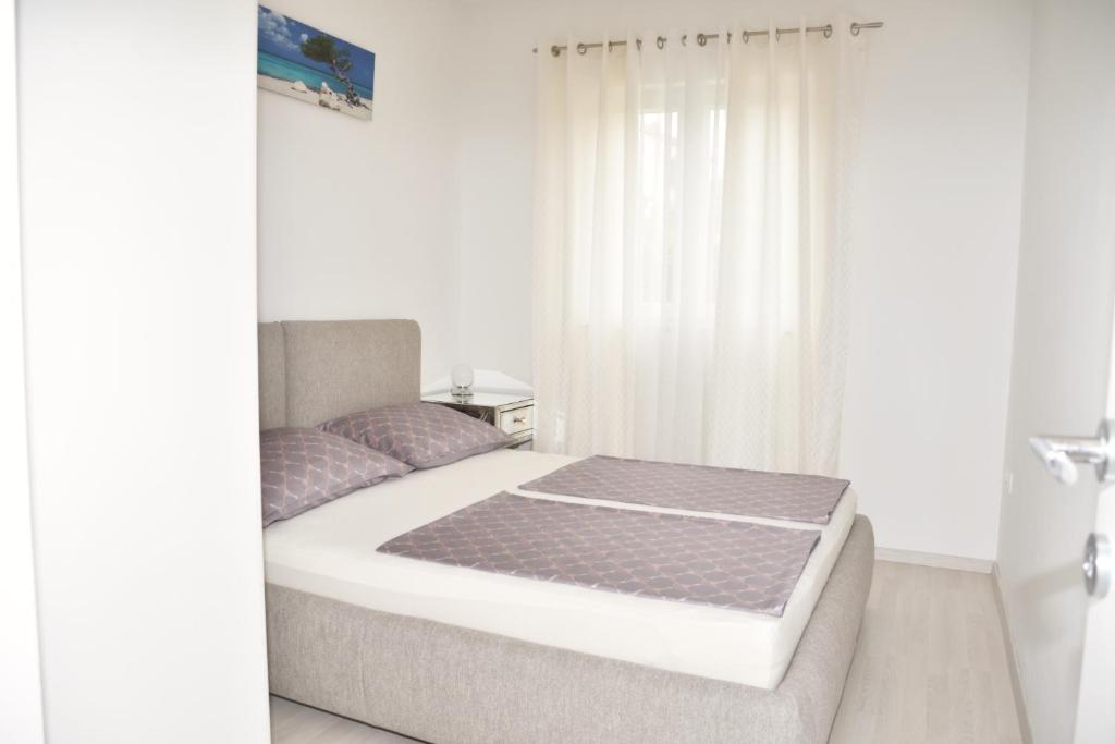 a bedroom with a large bed with a window at Apartment Josip 2 in Tribunj