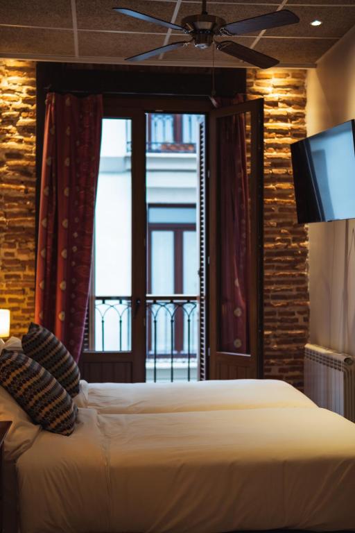 a bedroom with a bed and a television and a window at San Sebastián DOT Rooms in San Sebastián