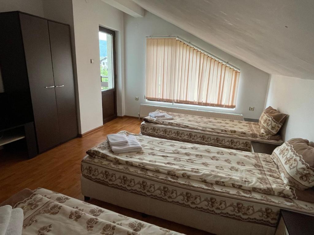 a room with three beds and a window at Къща за гости Александра in Dobrinishte