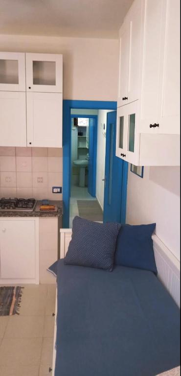a kitchen with white cabinets and a blue couch at Villa Vera trifamigliare con ingresso diretto 20 mt al mare clima wi-fi bbq in Cala Liberotto