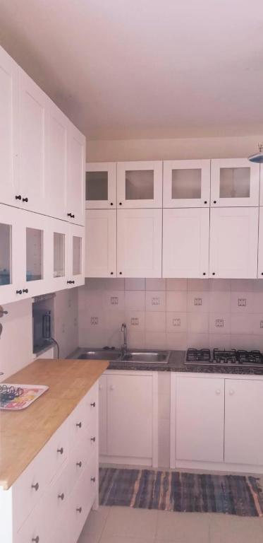 a white kitchen with white cabinets and a counter at Villa Vera trifamigliare con ingresso diretto 20 mt al mare clima wi-fi bbq in Cala Liberotto