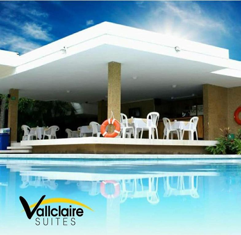 a swimming pool with white chairs and a swimming pool at Vallclaire Suites in Barranquilla