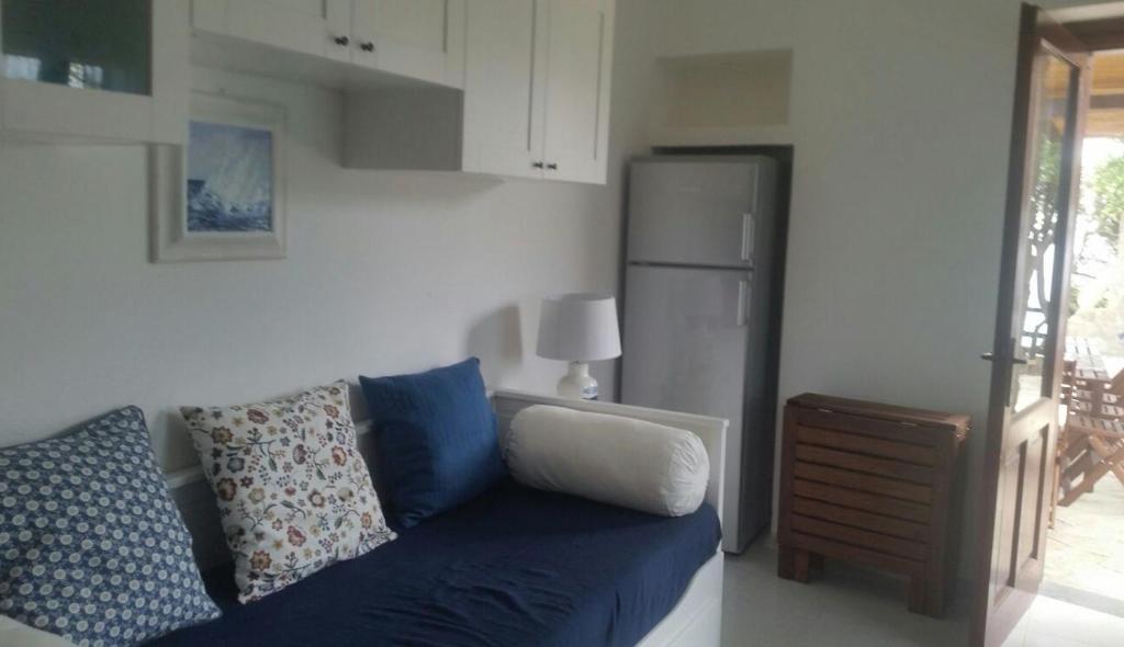 a living room with a blue couch and a refrigerator at Villa Vera trifamigliare con ingresso diretto 20 mt al mare clima wi-fi bbq in Cala Liberotto