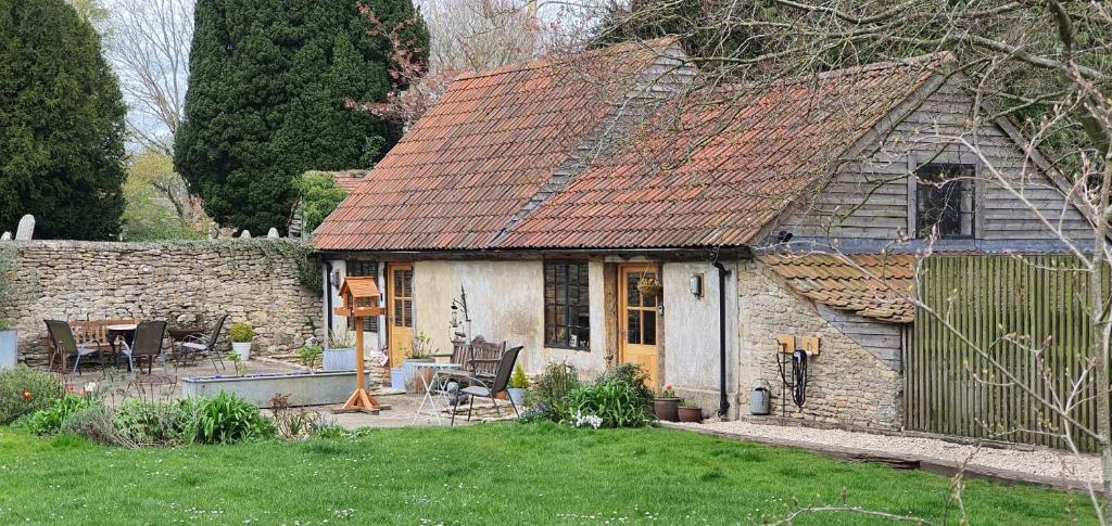 Luxury Barn House - Central Oxford/Cotswolds في Cassington: منزل حجري قديم مع طاولة وكراسي في ساحة
