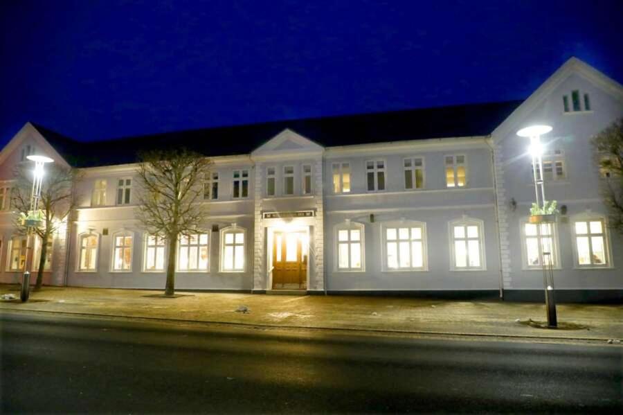 a large white building with lit up windows at night at Videbæk Hotel in Videbæk