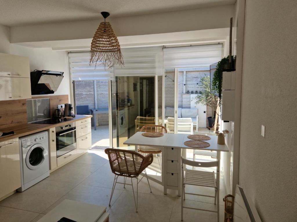 een keuken met een tafel en stoelen in een kamer bij Superbe appartement au coeur du Cap-Ferret in Cap-Ferret