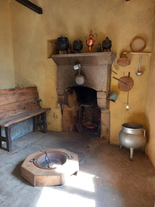 a room with a fireplace and a table and a toilet at Casa do Outeiro in Meda