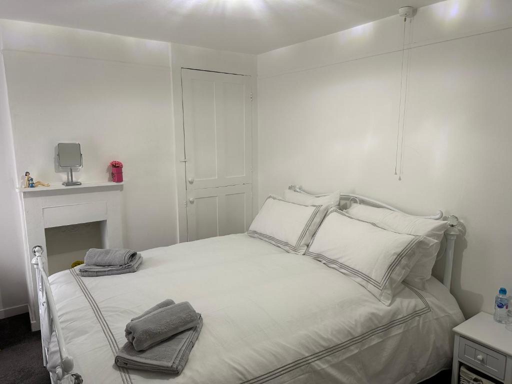een witte slaapkamer met een bed met twee handdoeken erop bij Cottage, 10 mins Train / River in Burnham on Crouch