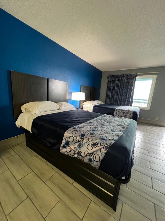 a bedroom with two beds and a blue wall at Executive Inn and Suites - Jackson in Jackson