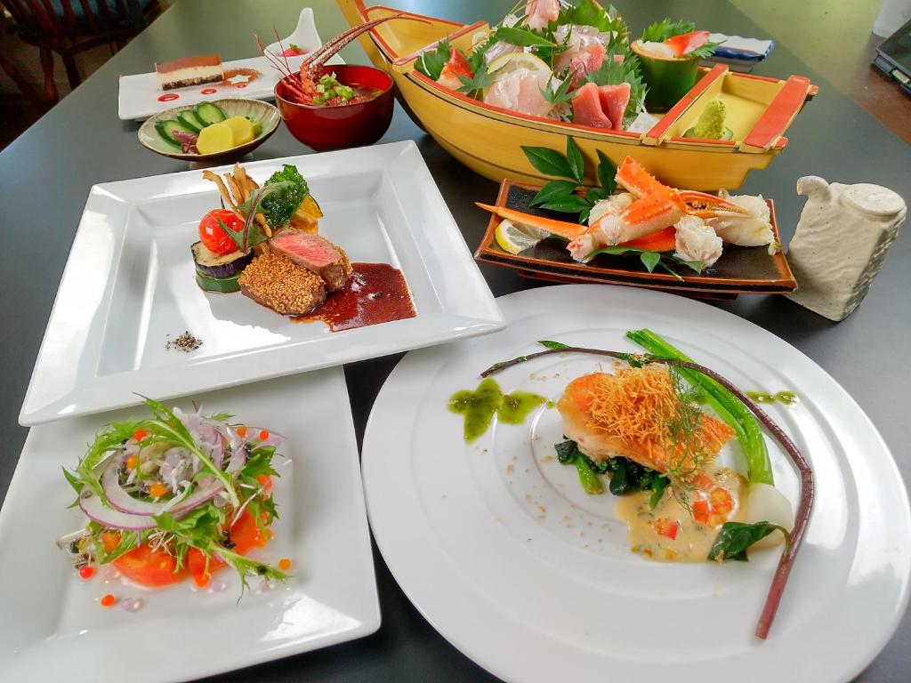 una mesa con tres platos de comida. en Koibito Misaki Pension Marine Mates, en Izu