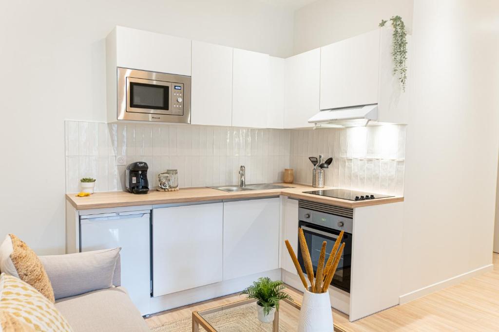 une cuisine avec des armoires blanches et un micro-ondes dans l'établissement Le naturel - Superbe logement - Extérieur privatif - Centre ville, au Mans