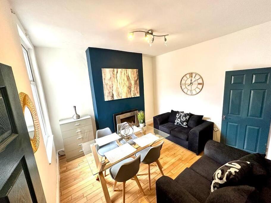 a living room with a black couch and a table at Princes Park semi with Jacuzzi sleeps 6 L8 in Liverpool